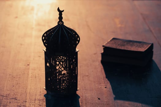 Ramadan Kareem background. Ornamental Arabic lantern glowing at night and the holy book of Quaran.