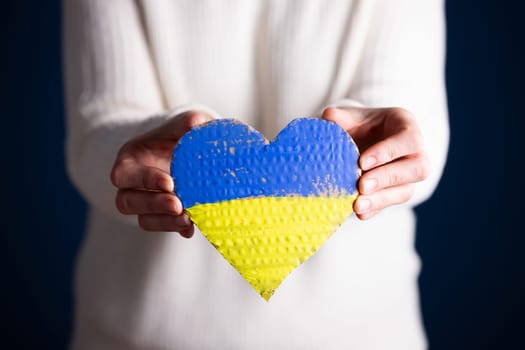 Heart shaped flag of Ukraine in female hands. The concept of solidarity with the citizens of Ukraine.