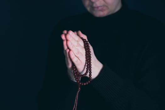 Religious young woman praying to God, on dark background.