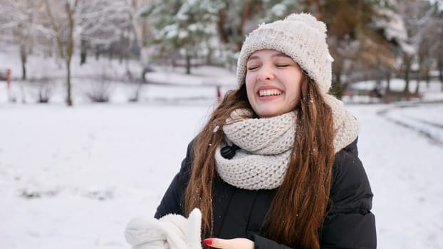 Young beautiful caucasian woman goulash in snowy winter forest close up in slow motion. Happy girl with long brown hair enjoys winter and smiles on Christmas Eve and Happy New Year