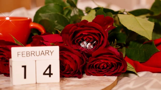 Background Festive Flatlay, composition for Valentine's Day on February 14. Coffee in a red cup, red rose flowers and diamond heart earrings at home in bed