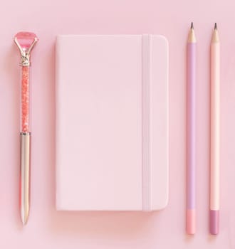 Pink notebook, pensils and decorative gemstone pen on light pink top view. Textbook mockup, planner cover with place fot text. Educational and girly concept