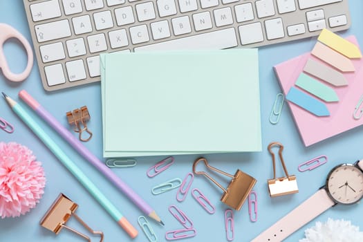 Paper card, Pink school accessories and keyboard on light blue , Top view, mockup. Girly workplace with notebook, scissors, pencil, pen, paperclips, cards and watch. Back to school