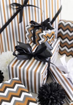 Gift boxes wrapped in Striped and chevron geometric paper with black ribbon bows near black and white decor close up. Christmas, New Year, Birthday, Anniversary concept