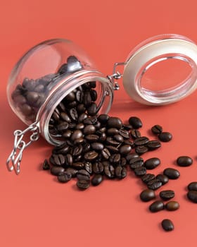 Roasted Coffee beans in a glass jar on pink background with copy space close up. Represent breakfast, energy, freshness or aroma