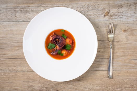Plate on a table with braised octopus in tomato dish