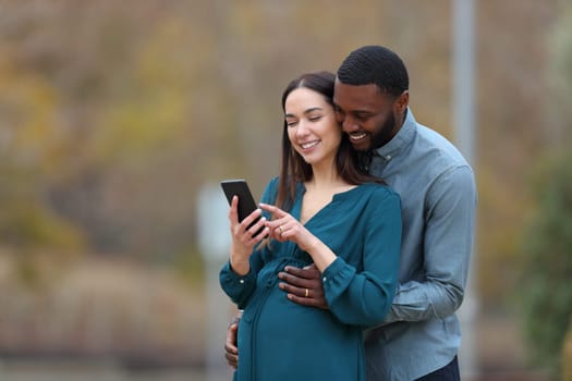 Pregnant wife and her husband checking smart phone