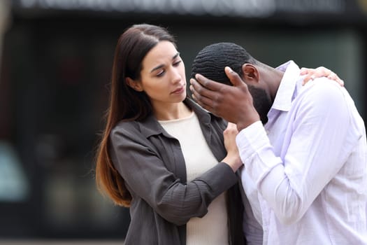 Woman comforting a sad friend in the street