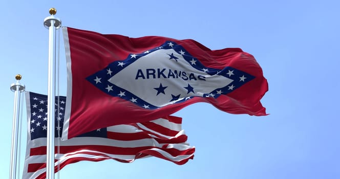 The flags of the Arkansas state and United States waving in the wind. Democracy and independence. US state flag