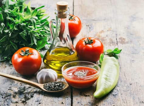 Olive oil, tomato and herbs on rustic wooden table