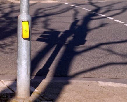 Shade of a traffic light on asphalt, yellow traffic light button for people with handicap/ debility of sight