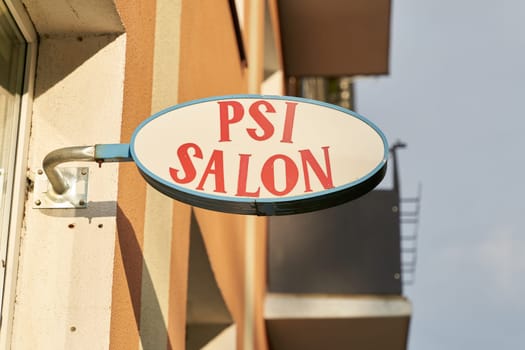Illuminated sign with the inscription Psi Salon (pet hairdresser) in the center of Kolobrzeg in Poland