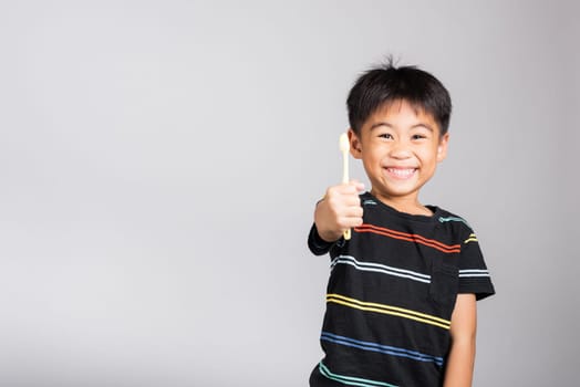 Little cute kid boy 5-6 years old show brush teeth and smile in studio shot isolated on white background, happy Asian children holding toothbrush in mouth by himself, Dental hygiene healthy concept
