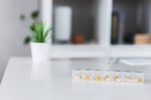 Closeup of medical pill box with doses of tablets for daily take a medicine with white, yellow drugs and capsules used for treatment, cure the disease. Healthy lifestyle, vitamins, omega-3 supplements