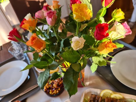 A bouquet of roses in a vase on a bedside table