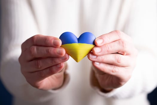 Heart shaped flag of Ukraine in female hands. The concept of solidarity with the citizens of Ukraine.