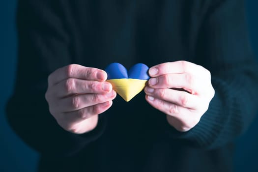 Heart shaped flag of Ukraine in female hands. The concept of solidarity with the citizens of Ukraine.