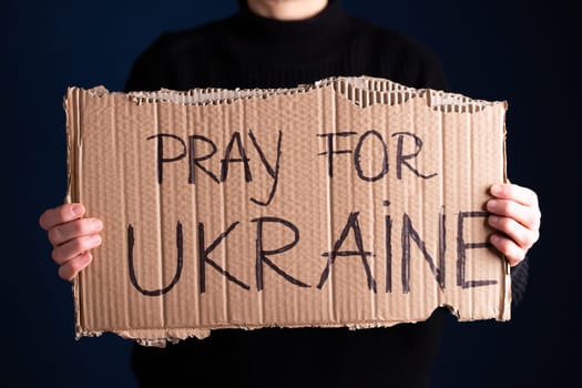Woman holds a banner with anti-war message. Protest against the Russian intervention to Ukraine, activism and human rights movement. Concept of standing with Ukrainian.