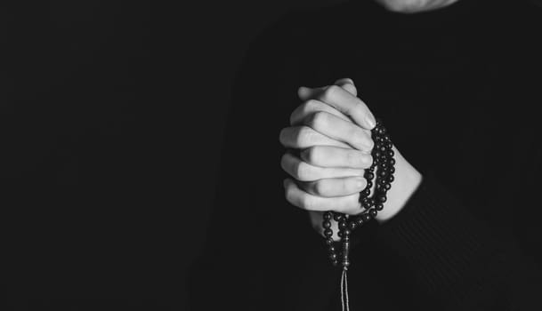 Religious young woman praying to God, on dark background.