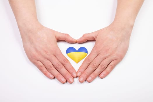 Heart shaped flag of Ukraine in female hands. The concept of solidarity with the citizens of Ukraine.