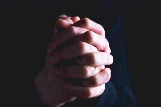 Praying hands with faith in religion and belief in God on dark background. Power of hope or love and devotion.