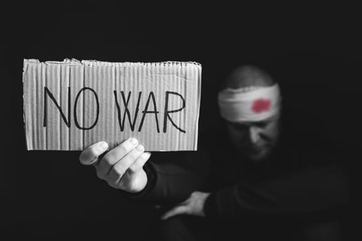 Wounded man holding placard with No war text. Stop war, russian aggression, freedom to Ukraine concept.