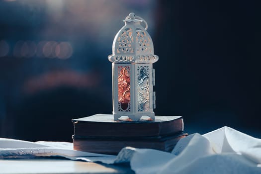 Ramadan Kareem background. Ornamental Arabic lantern glowing at night and the holy book of Quran.