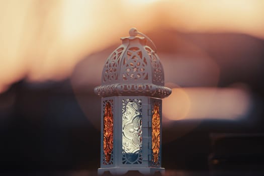 Ramadan Kareem background. Ornamental Arabic lantern glowing at night and the holy book of Quran.