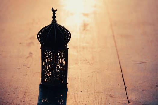 Ramadan Kareem background. Ornamental Arabic lantern on vintage wooden background in the sunset
