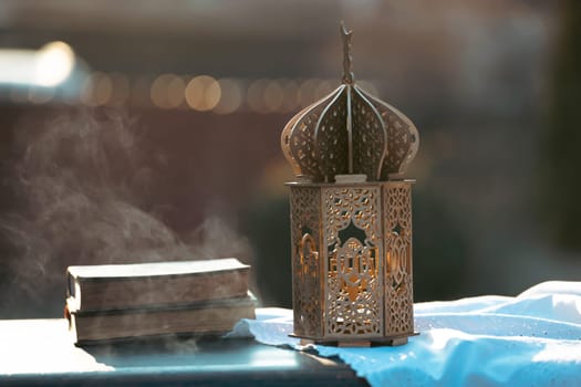 Ramadan Kareem background. Ornamental Arabic lantern glowing at night and the holy book of Quran.