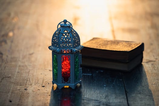 Ramadan Kareem background. Ornamental Arabic lantern glowing at night and the holy book of Quran.