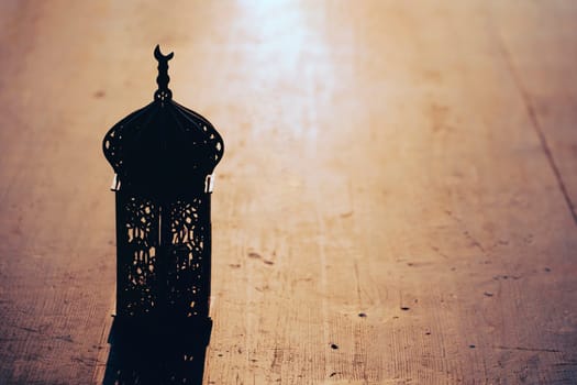 Ramadan Kareem background. Ornamental Arabic lantern on vintage wooden background in the sunset