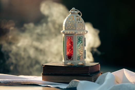 Ramadan Kareem background. Ornamental Arabic lantern glowing at night and the holy book of Quran.