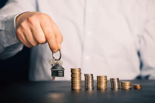 Businessman with house model and piles of coins.Realtor, mortgage, saving money, home loan concept.