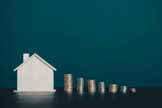 Coin stack with house model on table with copy space. Realtor, mortgage, your house, home loan concept.