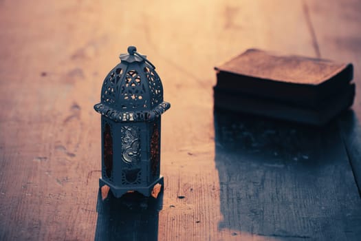 Ramadan Kareem background. Ornamental Arabic lantern glowing at night and the holy book of Quran.