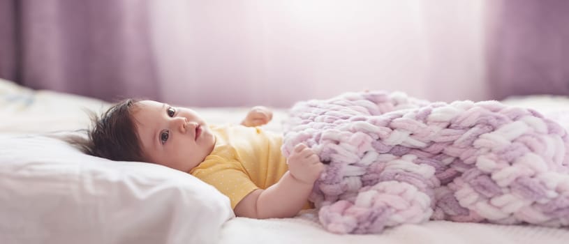 Cute little baby lying under pink blanket. Concept of childhood and maternity.