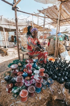 Mojo, Oromia Region, Ethiopia - May 16, 2019: Woman at the market selling teapots for traditional ethiopian bunna coffeen in Mojo city, Oromia Region, Ethiopia, Africa
