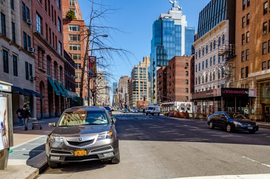 City Street in Chelsea with cars parked next to the street, sidewalk with people, different office building facades and traffic during sunny winter day, horizontal