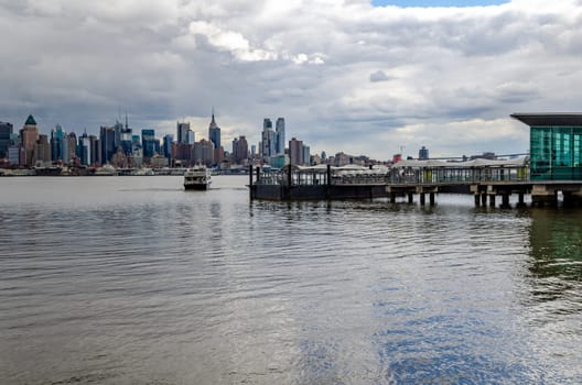 Port Imperial / Weehawken Ferry Terminal at Hudson River, New Jersey with Ferry, side view during cloudy winter day, horizontal
