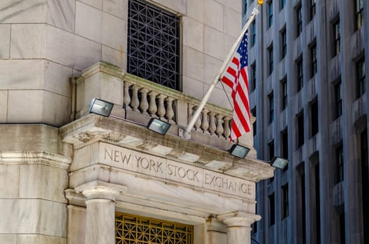 New York Stock Building Exchange golden colored Building Entrance, close-up with American Flag above during winter, vertical