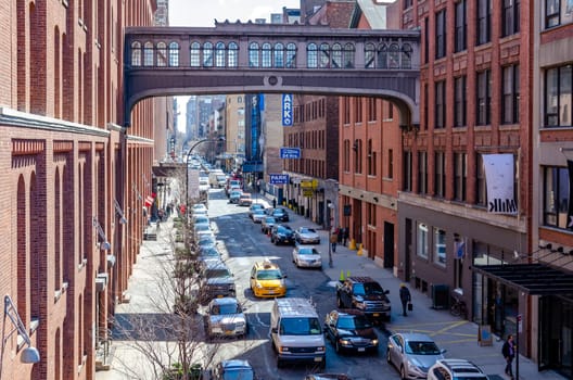 City street in Chelsea with yellow taxi cab and van passing by, aerial view from the High Line Rooftop Park, Bridge between two office Buildings, New York City during sunny winter day, horizontal