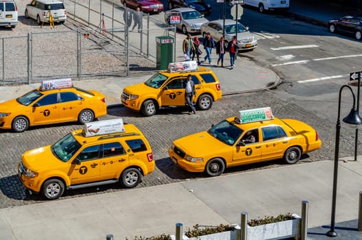 Different car models of Yellow taxi cabs parked in side street in Chelsea, New York City during sunny winter day, horizontal