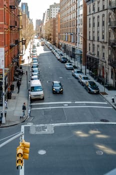 City street with parked cars and traffic in Chelsea aerial view from the High Line Rooftop Park, New York City during sunny winter day, vertical