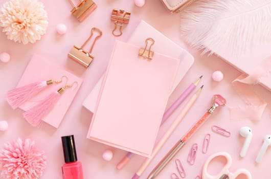 Paper with a clip and Pink school accessories on pastel pink, top view, mockup. Girly workplace with scissors, pencils, pen, paperclips, earrings and nail polish. Back to school concept