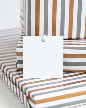 Presents with blank square gift tag close up. Gift boxes wrapped in Striped geometric paper. Christmas, New Year, Birthday, Anniversary label mockup