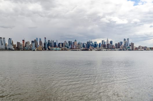Wide angle shot of New York City Manhattan Skyline with Empire State Building and Hudson river in front during cloudy winter day, horizontal