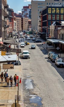 Chelsea City Street with people walking on sidewalk and traffic on the street, lots of cars parked on the street, aerial view during sunny winter day, puddle on the street, vertical