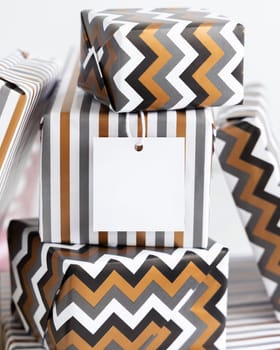 Present with blank square gift tag close up. Gift boxes wrapped in Striped and chevron geometric paper. Christmas, New Year, Birthday, Anniversary label mockup