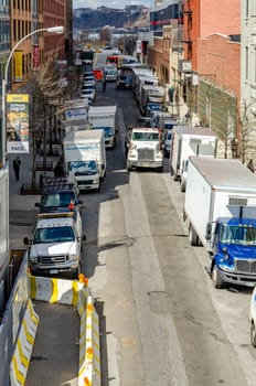 Lots of different trucks parked in a side street in Chelsea, aerial view, Truck passing by, New York City during sunny winter day, vertical